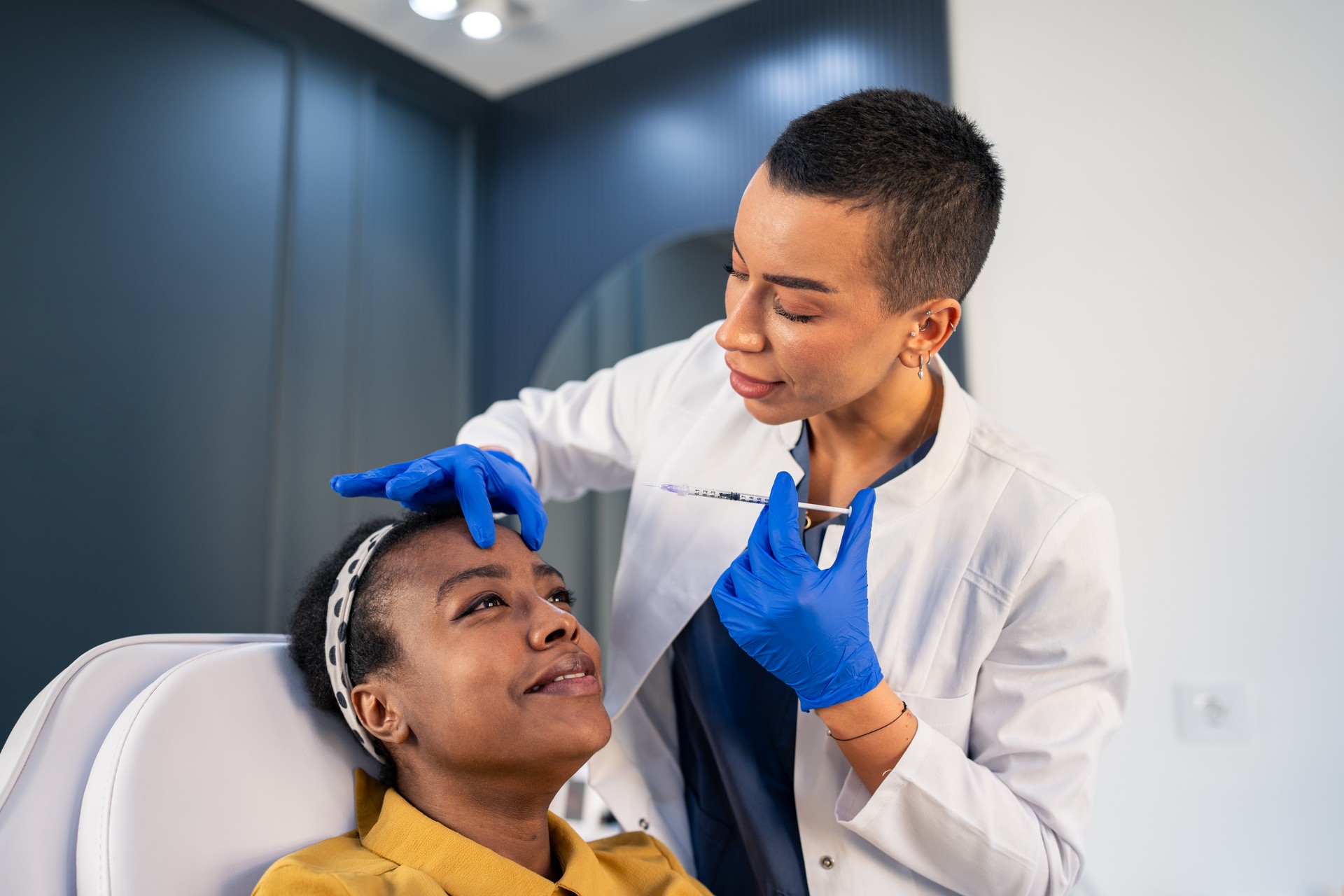 Mulher africana sorridente está recebendo injeções faciais rejuvenescedoras na clínica de estética